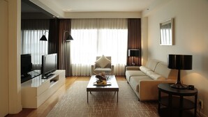 A modern living room with a flat-screen TV, a sofa, a coffee table, and a lamp. - Hotel Kukdo (Seoul)