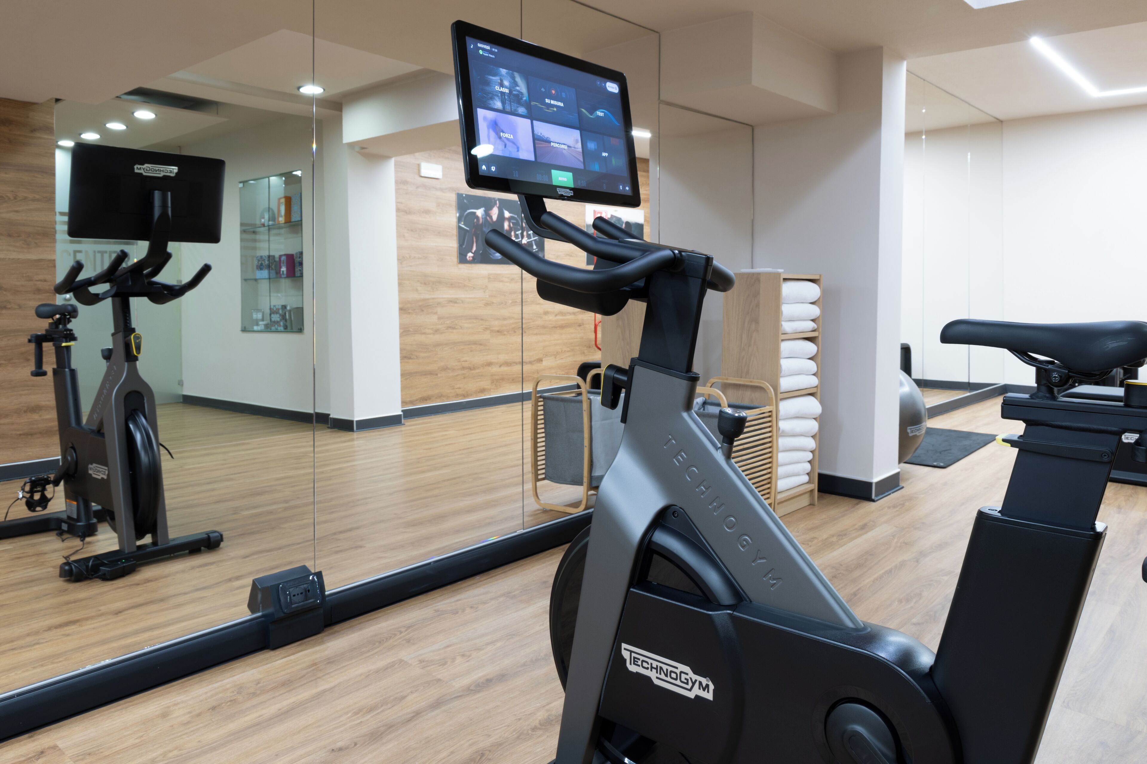 Un gimnasio con equipo de ejercicio, una pantalla digital y un espejo.