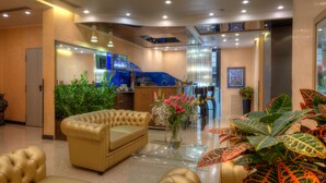 A hotel lobby with a reception desk, seating area, and decorative plants. - Central Park Hotel Modena (Modena)