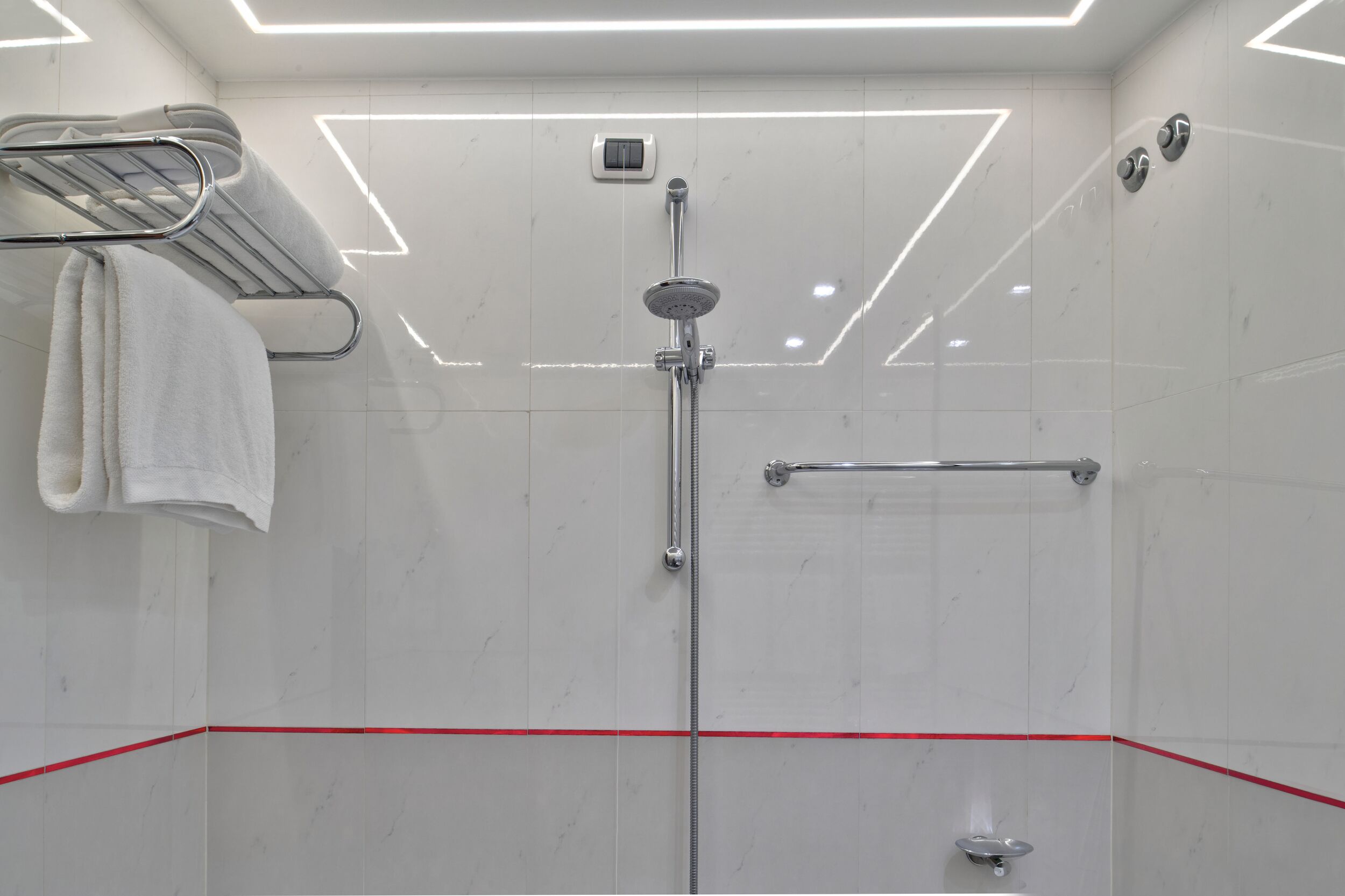 Un bagno moderno con doccia, asciugamano e una linea rossa che segna il pavimento.