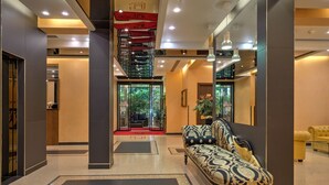 A modern lobby with a patterned sofa, a staircase, and a glass door leading to a seating area. - Central Park Hotel Modena (Modena)
