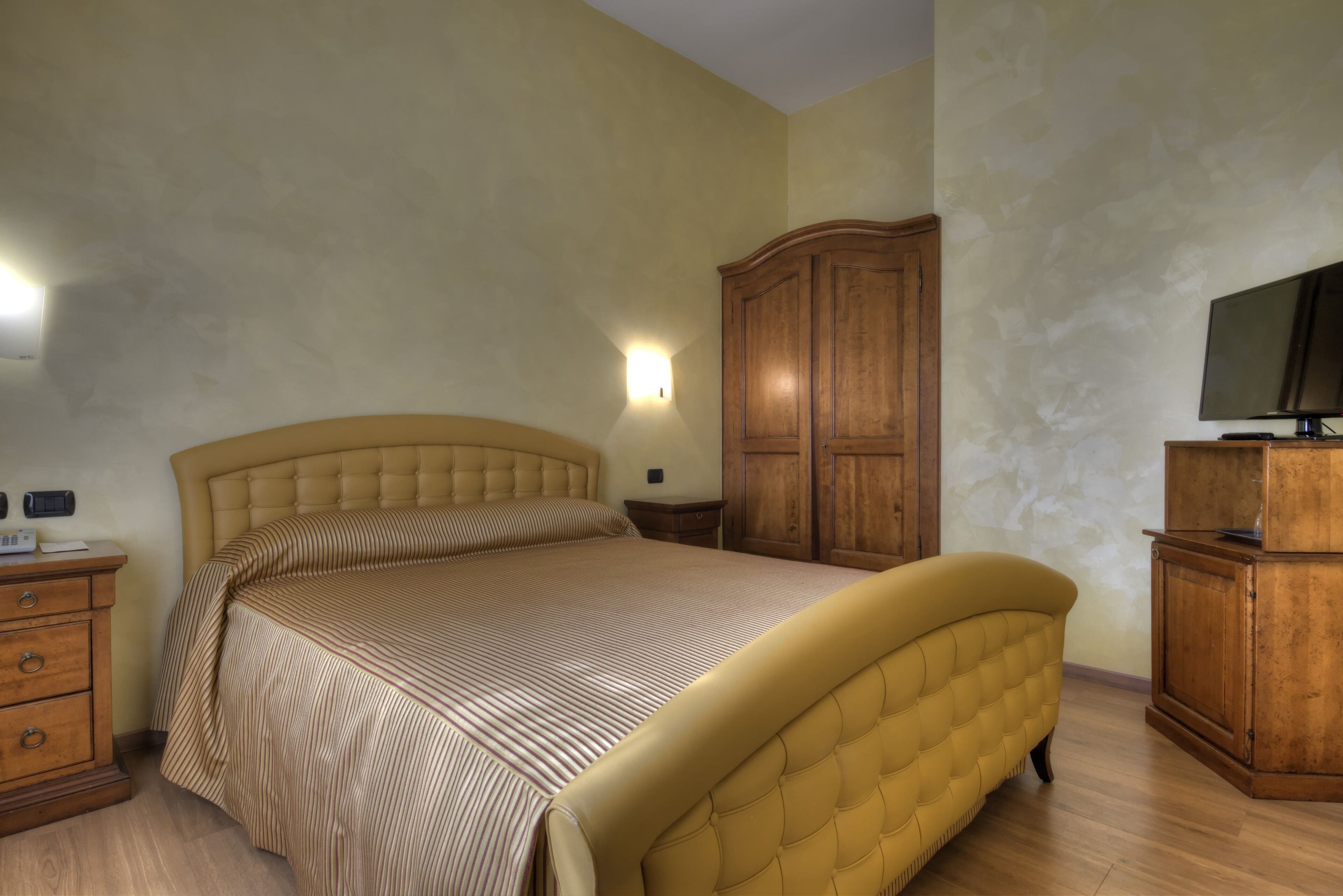 Ein Schlafzimmer mit einem großen Bett, einem Holzschrank und einem Fernseher auf einem Schrank.