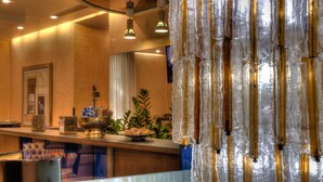 A hotel reception area with a wooden counter, a framed picture on the wall, and a decorative hanging structure. - Central Park Hotel Modena (Modena)