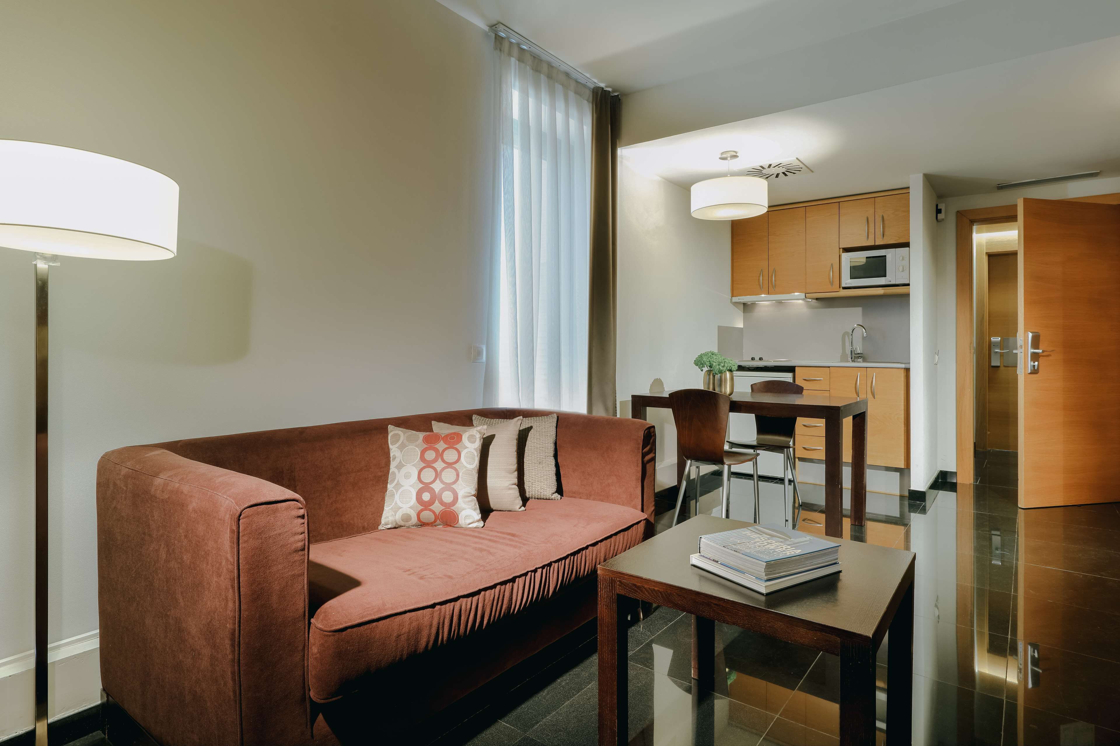 A modern living room with a sofa, a coffee table, and a dining area with a chair and a table.