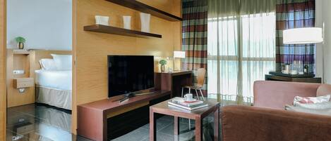 Ein modernes Hotelzimmer mit Flachbildfernseher, einer Couch, einem Couchtisch und einem TV-Schrank.