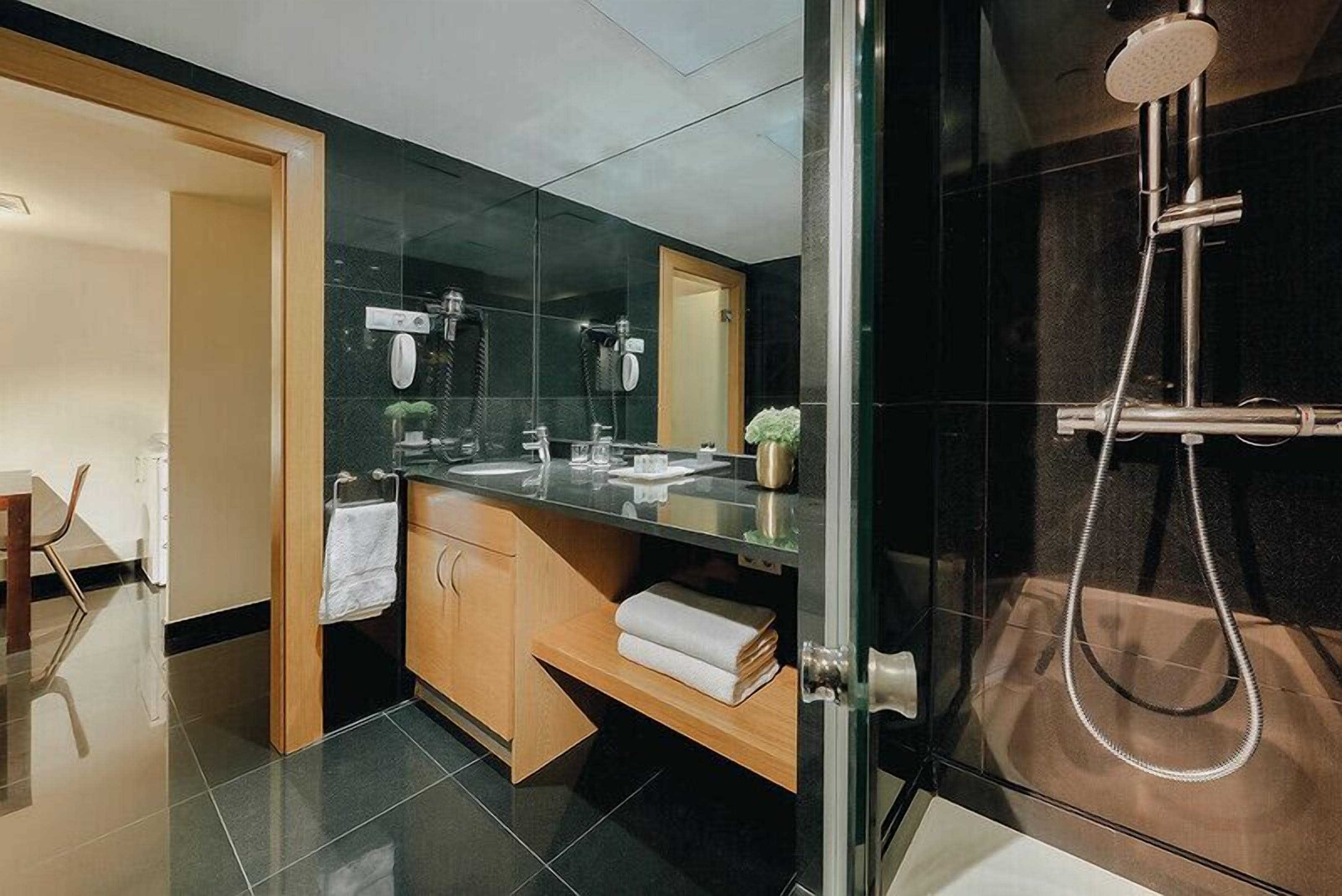Un bany modern amb un espai de banyera de vidre, un lavabo amb mirall i un para-tovalloles.