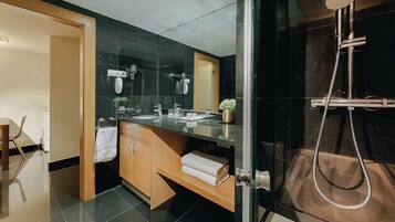 Un bany modern amb un espai de banyera de vidre, un lavabo amb mirall i un para-tovalloles.