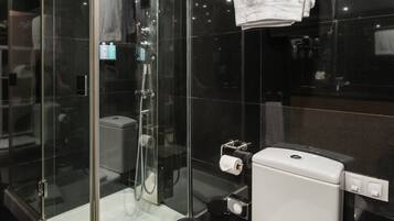 Un baño moderno con cabina de ducha de vidrio, inodoro blanco y toallero.