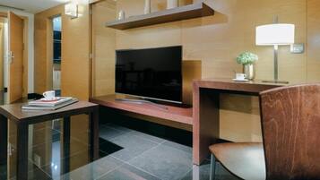 Una habitación de hotel moderna con una televisión de pantalla plana, una mesa consola de madera, una silla y una mesita con una taza y un libro.
