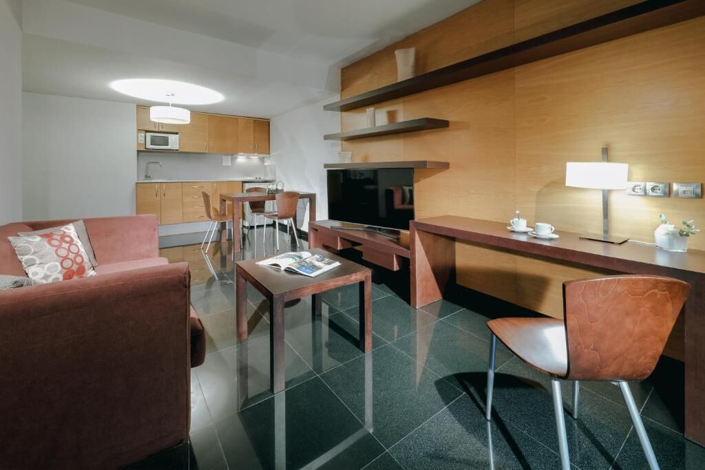 Un espacio habitable compacto con kitchenette, un sofá, una mesa de comedor y un televisor.