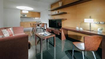 Un espacio habitable compacto con kitchenette, un sofá, una mesa de comedor y un televisor.