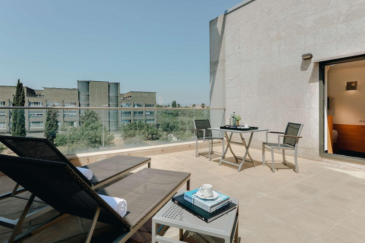 A balcony with lounge chairs, a table with chairs, and a view of buildings and trees.