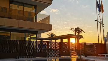 Un bâtiment moderne avec une piscine qui reflète les couleurs du coucher de soleil.