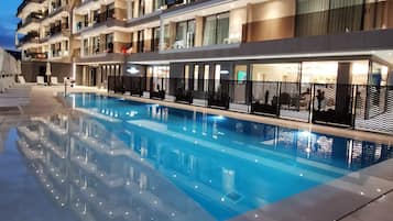 Een seizoensgebonden buitenzwembad en ligstoelen