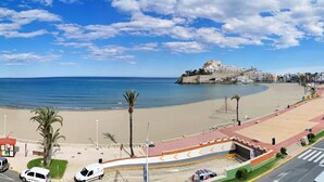 A coastal cityscape with a beach, palm trees, and a historic fort. - Hotel & Spa Castillo de Peñíscola (Peniscola)