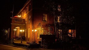 A brick building with a porch, illuminated by exterior lights.
