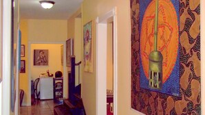 A hallway with a patterned wall, a staircase, and a door leading to another room.