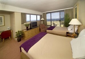 Ett hotellrum med två sängar, en TV, ett skrivbord och en balkong med utsikt.