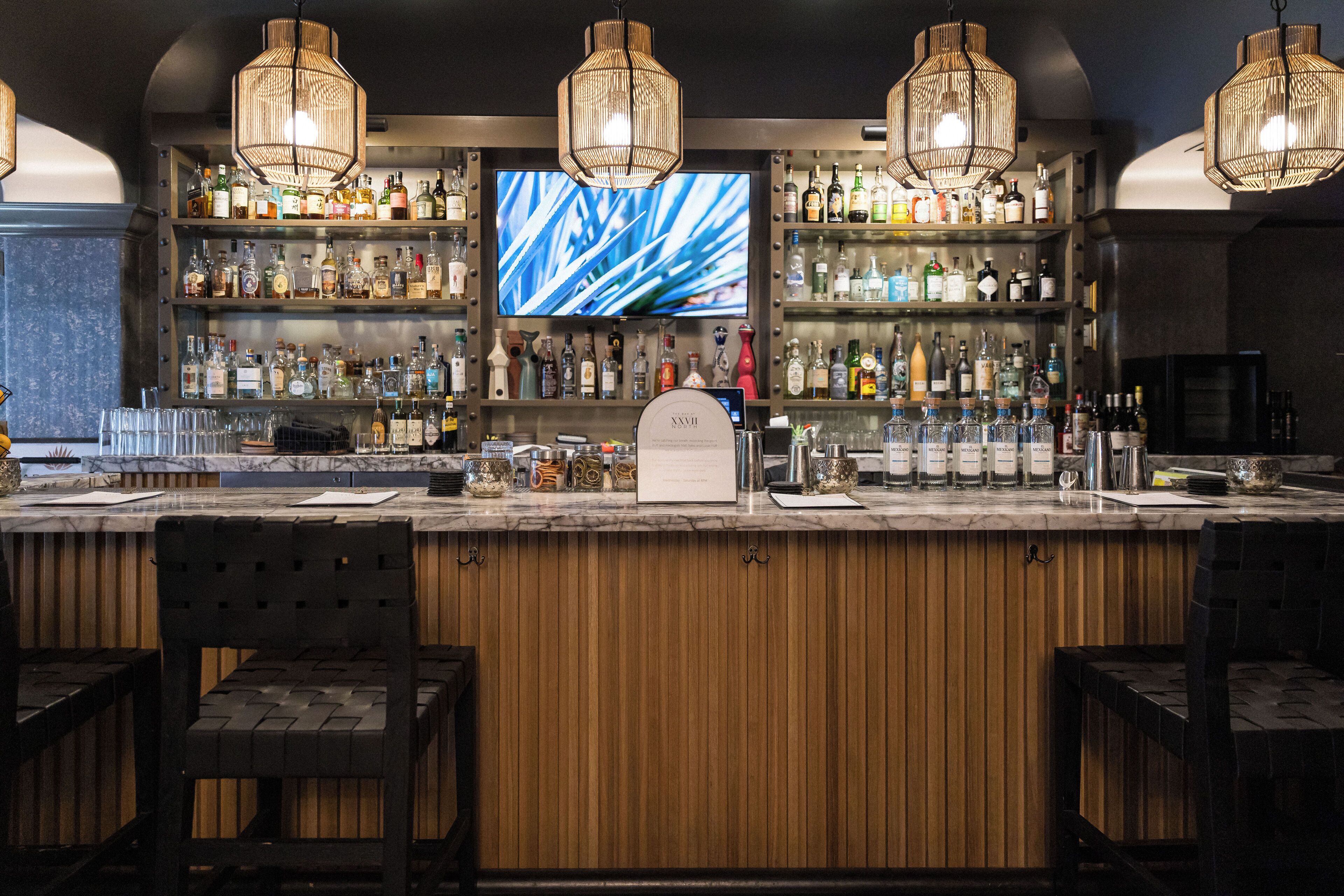 A bar area with wooden paneling, a large TV screen, and multiple liquor bottles.