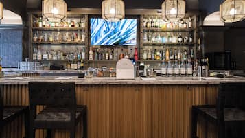Een bar met houten lambrisering, een groot televisiescherm en diverse drankflessen.