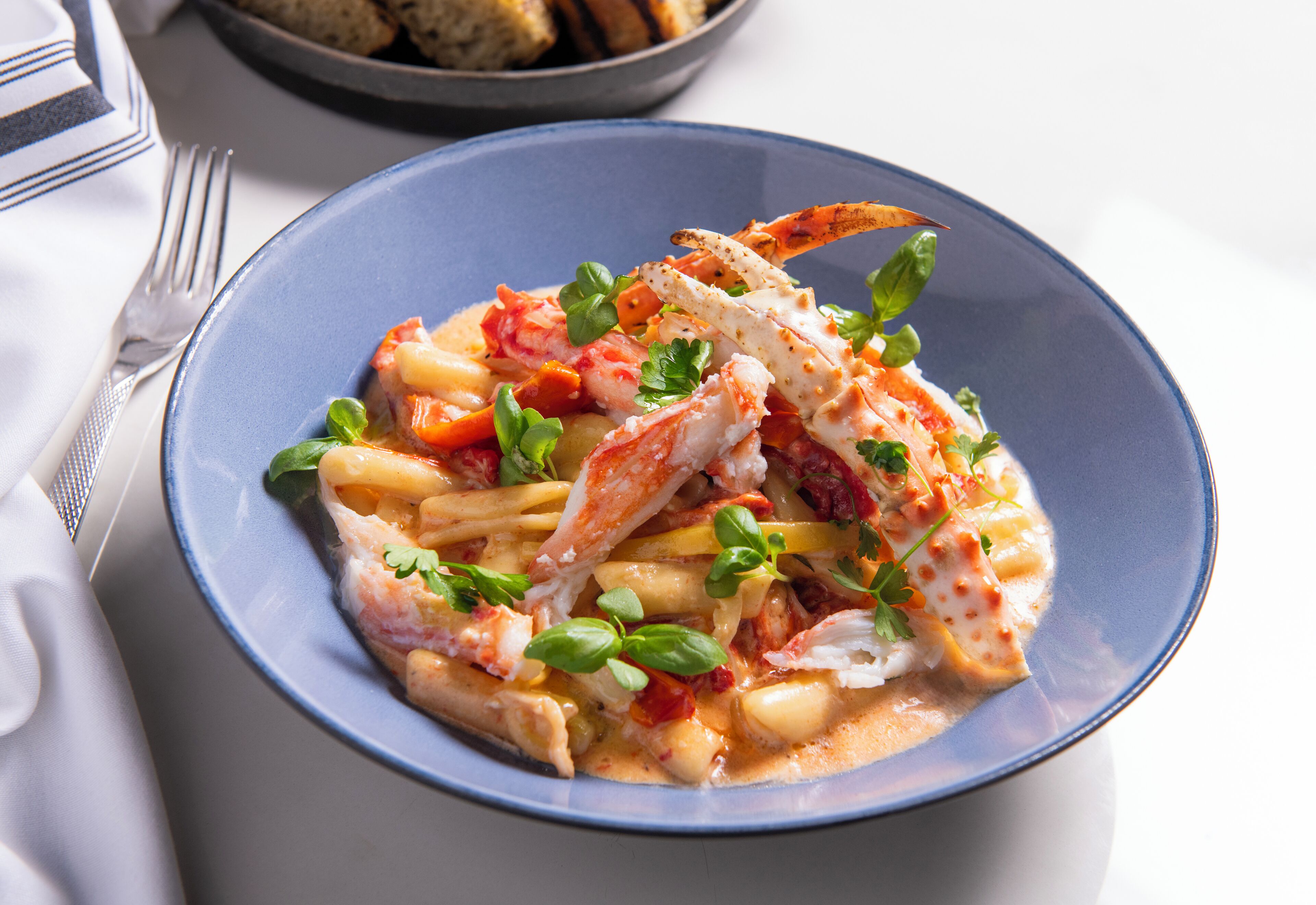 Un plato de pasta con langosta, adornado con hierbas.