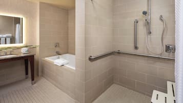 A modern bathroom with a bathtub, a shower with grab bars, and a vanity with a mirror.