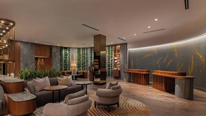 Ein moderner Lounge-Bereich mit Sitzgelegenheiten, einem Empfangstresen und einer Wand mit vertikaler Bepflanzung.