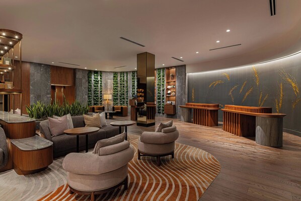 A modern lounge area with seating, a reception desk, and a wall with vertical greenery.