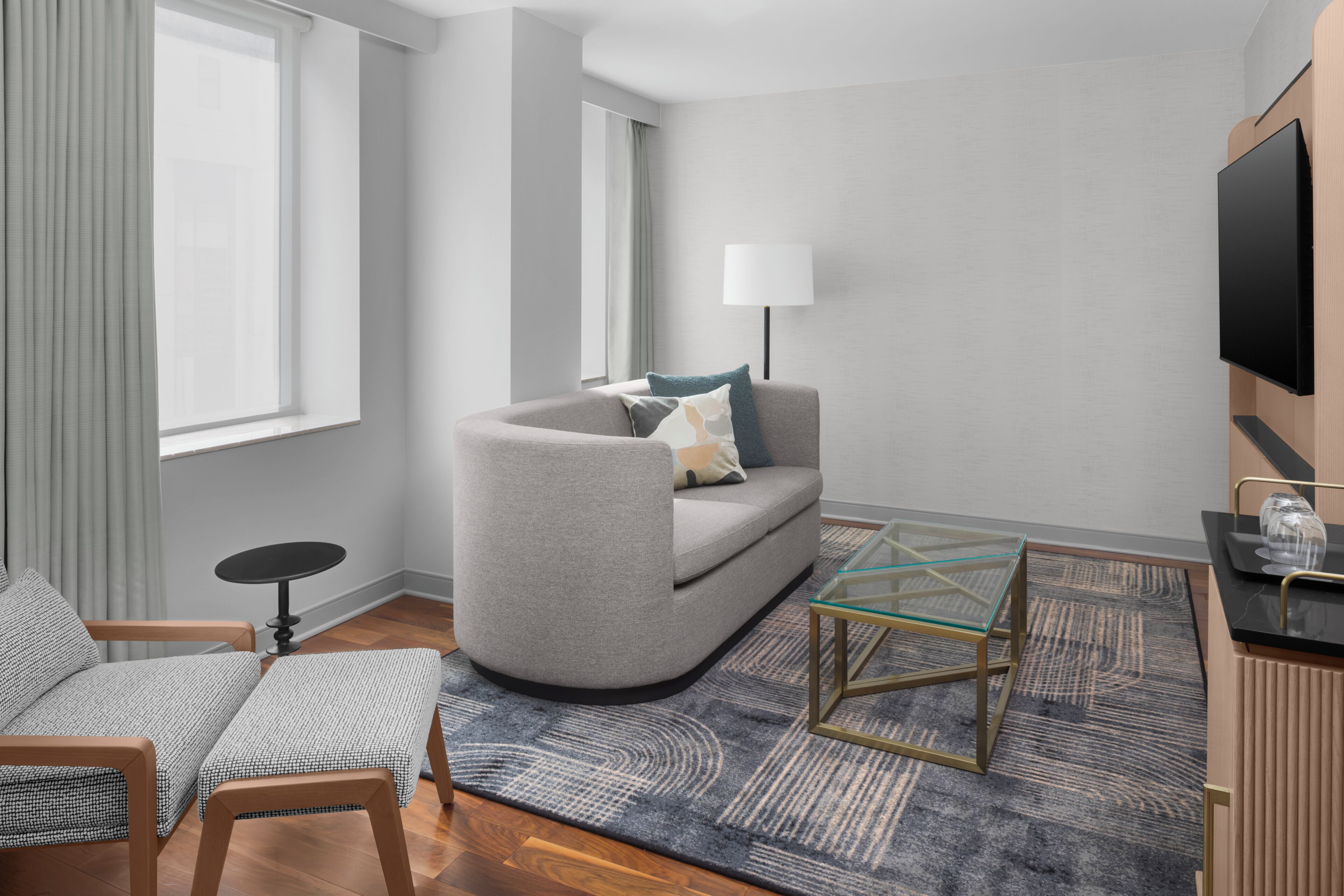 A modern living room with a sofa, a glass coffee table, a TV, and a lamp.