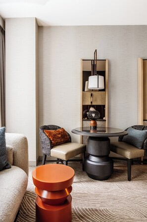 Une chambre d’hôtel moderne avec une table à manger ronde, deux canapés, une table basse et une lampe.