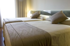 Hotellihuone, jossa on kaksi sänkyä, ja jokaisessa sängyssä on pääty ja tyynyt.