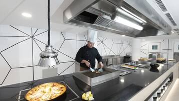 Una cocina moderna con un chef preparando comida, una parrilla grande y una disposición tipo bufé.
