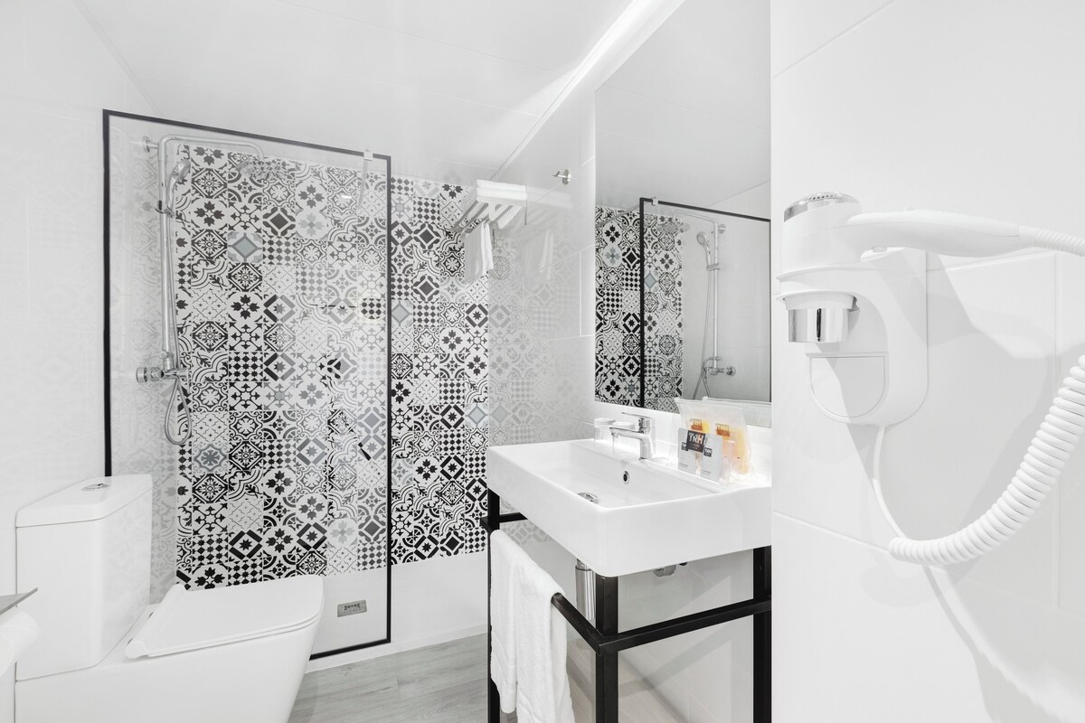 A modern bathroom with patterned tiles, a white sink, and a hairdryer.