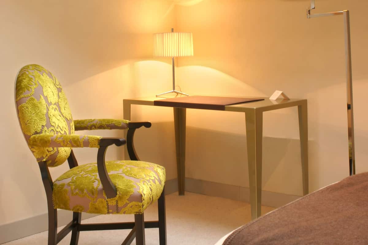 A room with a skylight, a chair, a table, and a floor lamp.