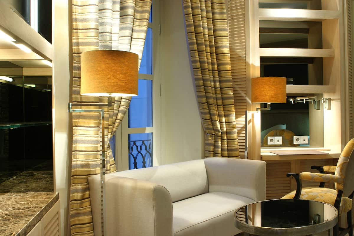 A modern hotel room with a sofa, a round table, and two lamps.