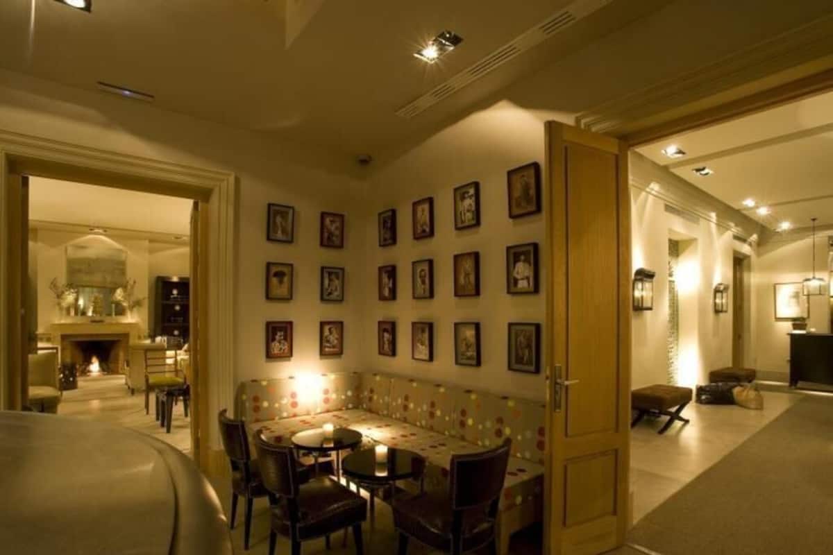 A dining area with a round table and chairs, a sofa, and a wall with framed pictures.