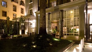 A well-lit hotel courtyard with a palm tree, a fountain, and a seating area. - Villa Oniria (Granada)