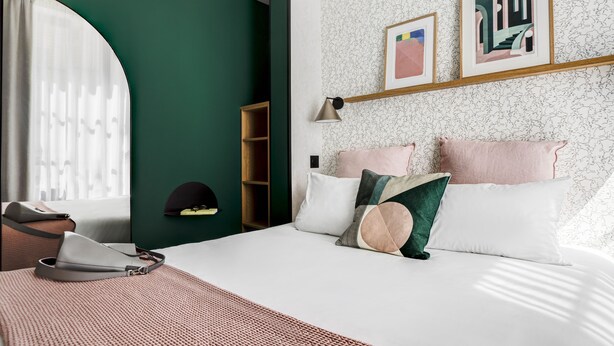 A bedroom with a bed, pillows, a bedside table, a lamp, a wardrobe, and a window with curtains. - Republik Hôtel (Lyon)