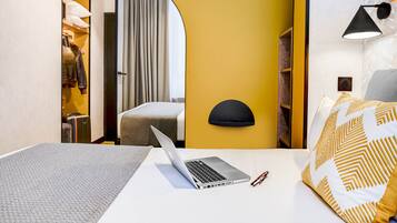 A hotel room with a bed, a laptop, and a suitcase.