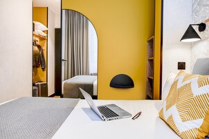 Una camera d'albergo con un letto, un portatile e una valigia.