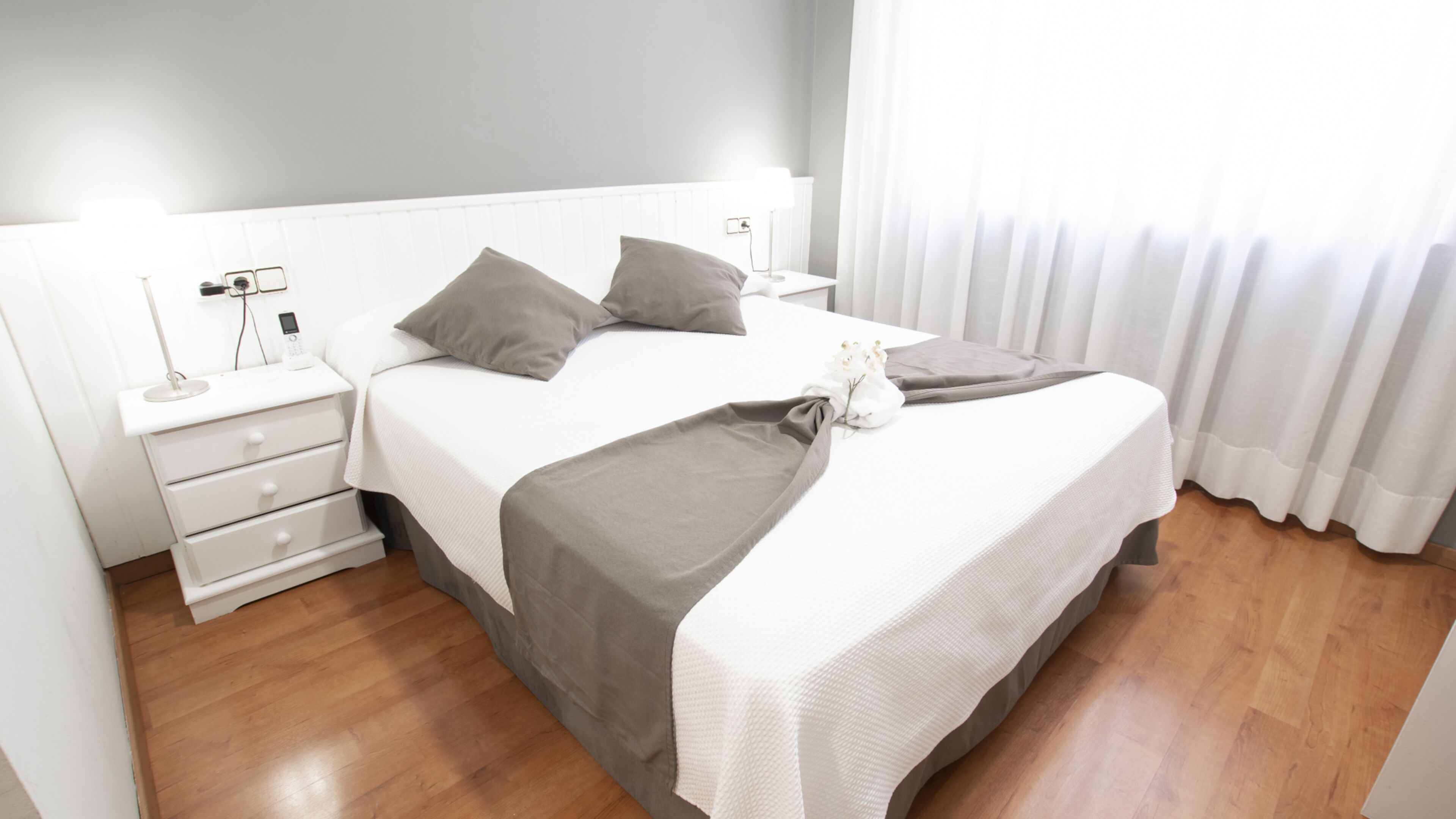 A neatly arranged hotel room with a bed, bedside tables, and a nightstand.