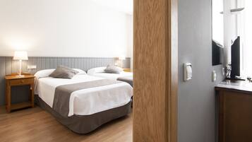 Habitación de hotel con dos camas, mesitas de noche de madera, un escritorio y un espejo.