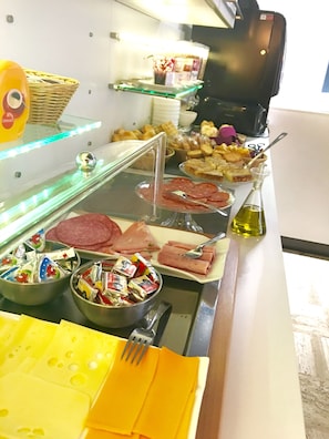 Un buffet proposant une variété de plats, notamment des viandes, des fromages et des condiments.