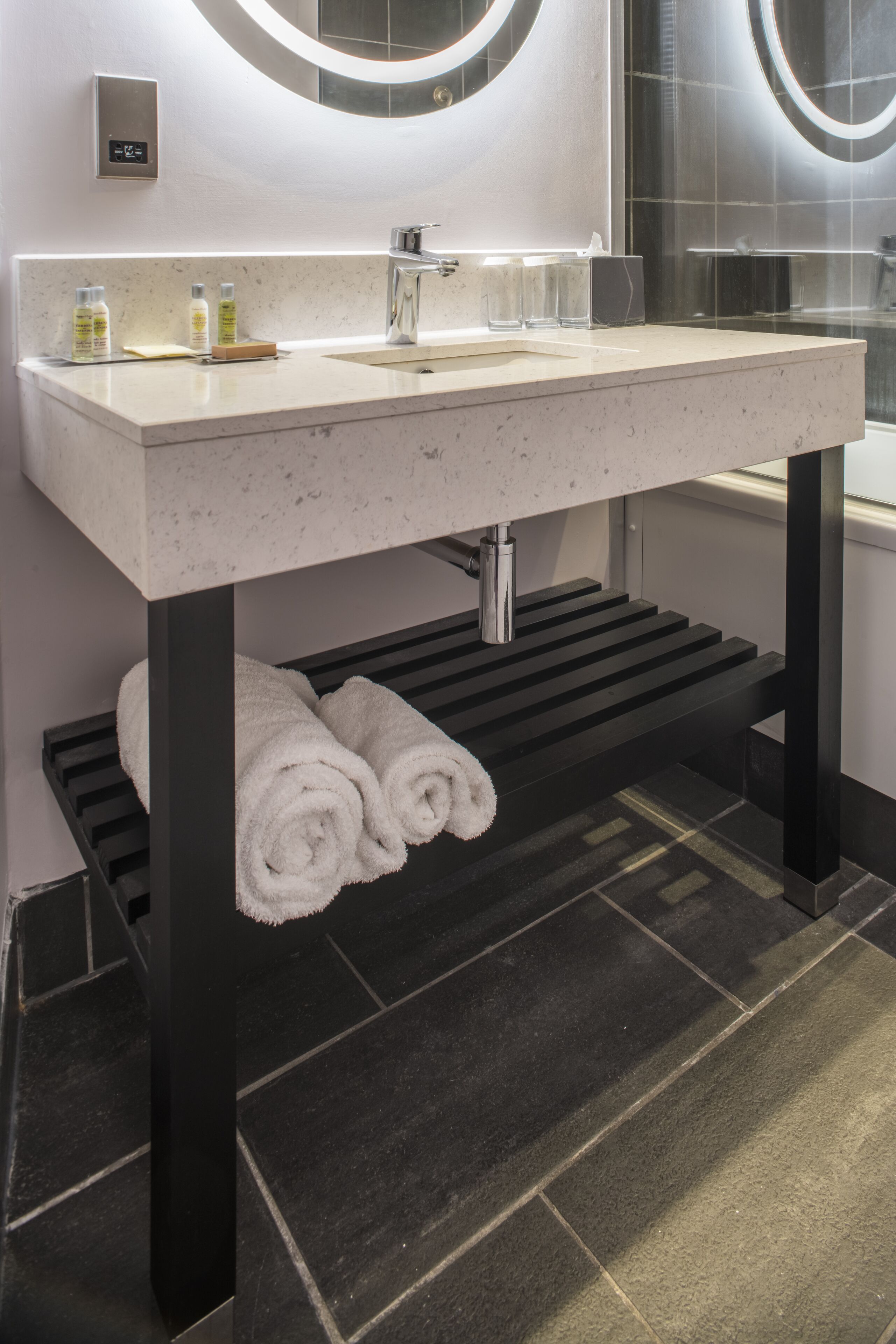 A modern bathroom with a white sink, a mirror, and a towel rack.