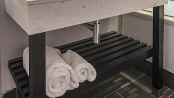 A modern bathroom with a white sink, a mirror, and a towel rack.