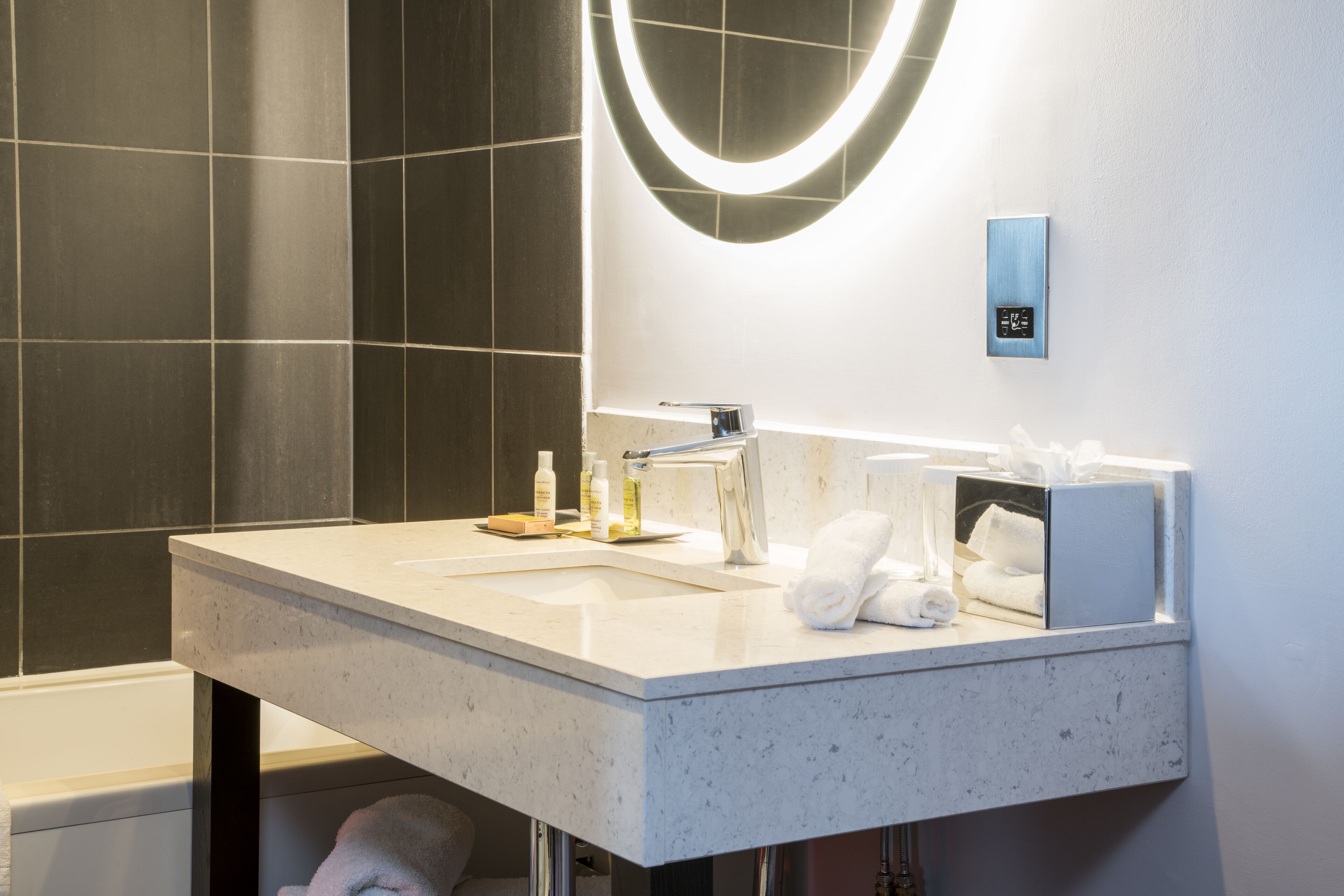A modern bathroom with a white sink, a mirror, and a towel rack.