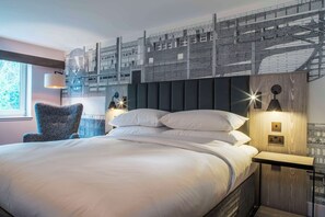 A modern hotel room with a large bed, a chair, and a wall-mounted light fixture. - DoubleTree by Hilton Hotel Bristol South - Cadbury House (Bristol)