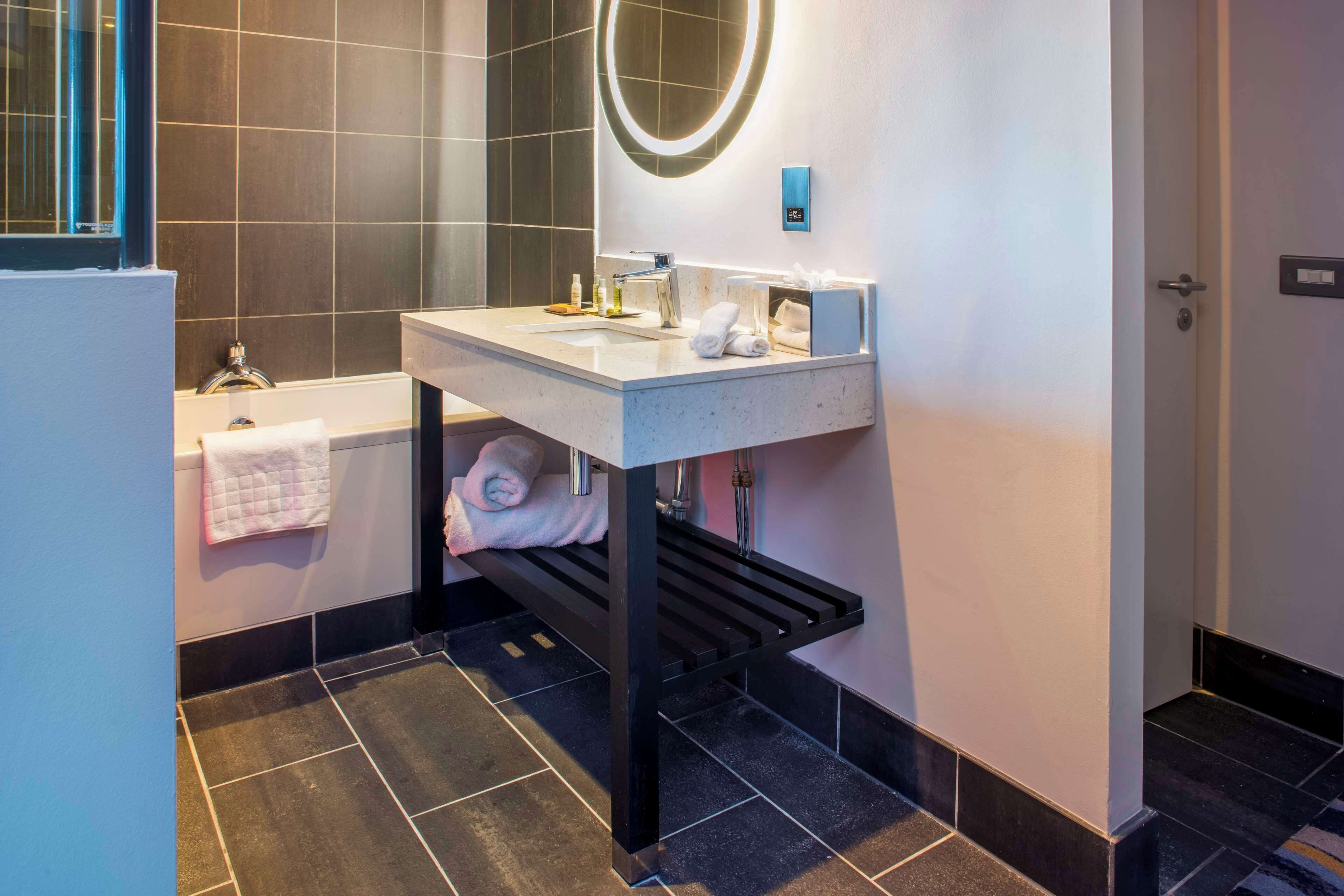 Een moderne badkamer met een bad, een wastafel met spiegel en een handdoekrek.