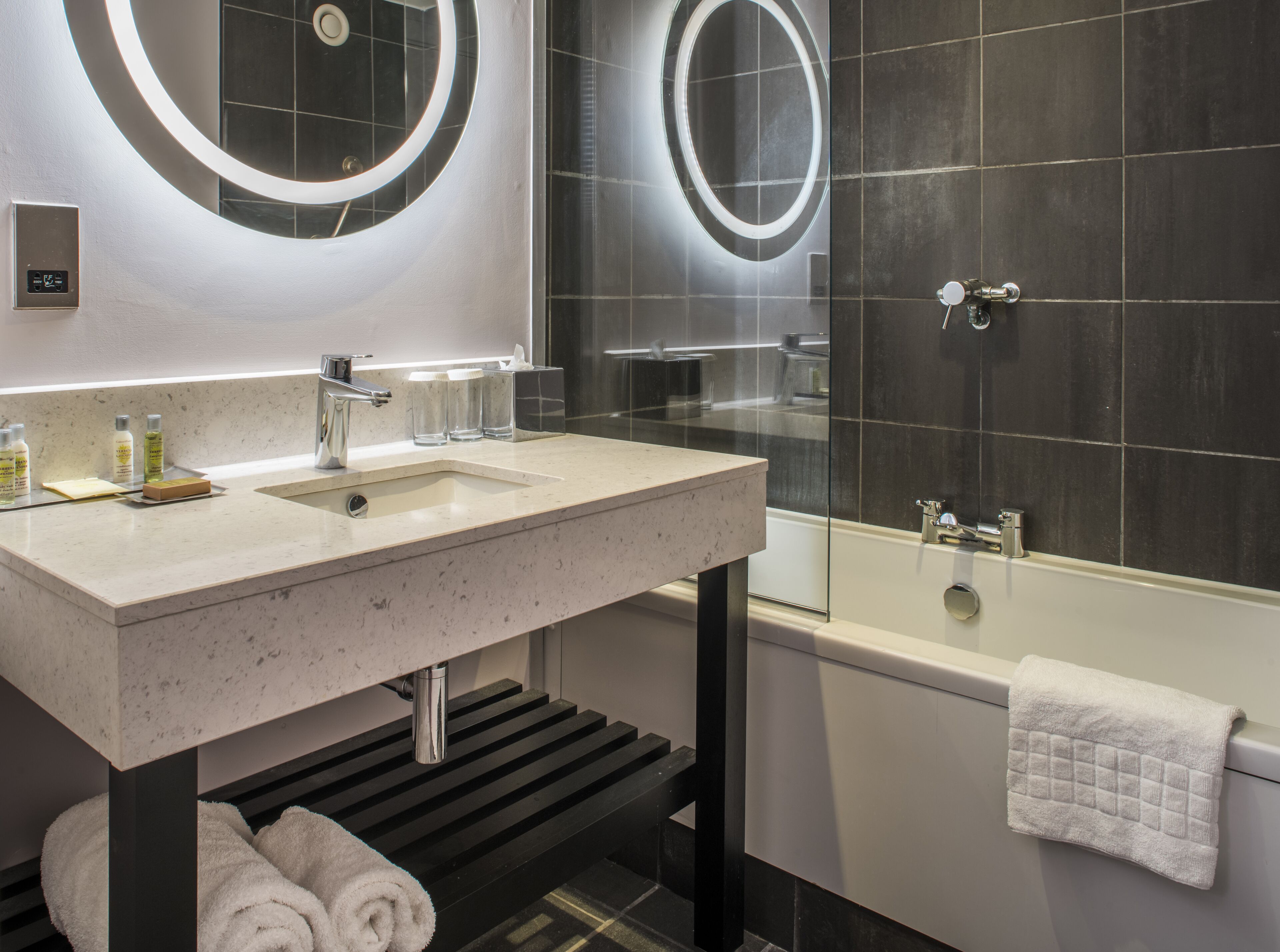 A modern bathroom with a large sink, a glass-enclosed shower, and a towel rack.