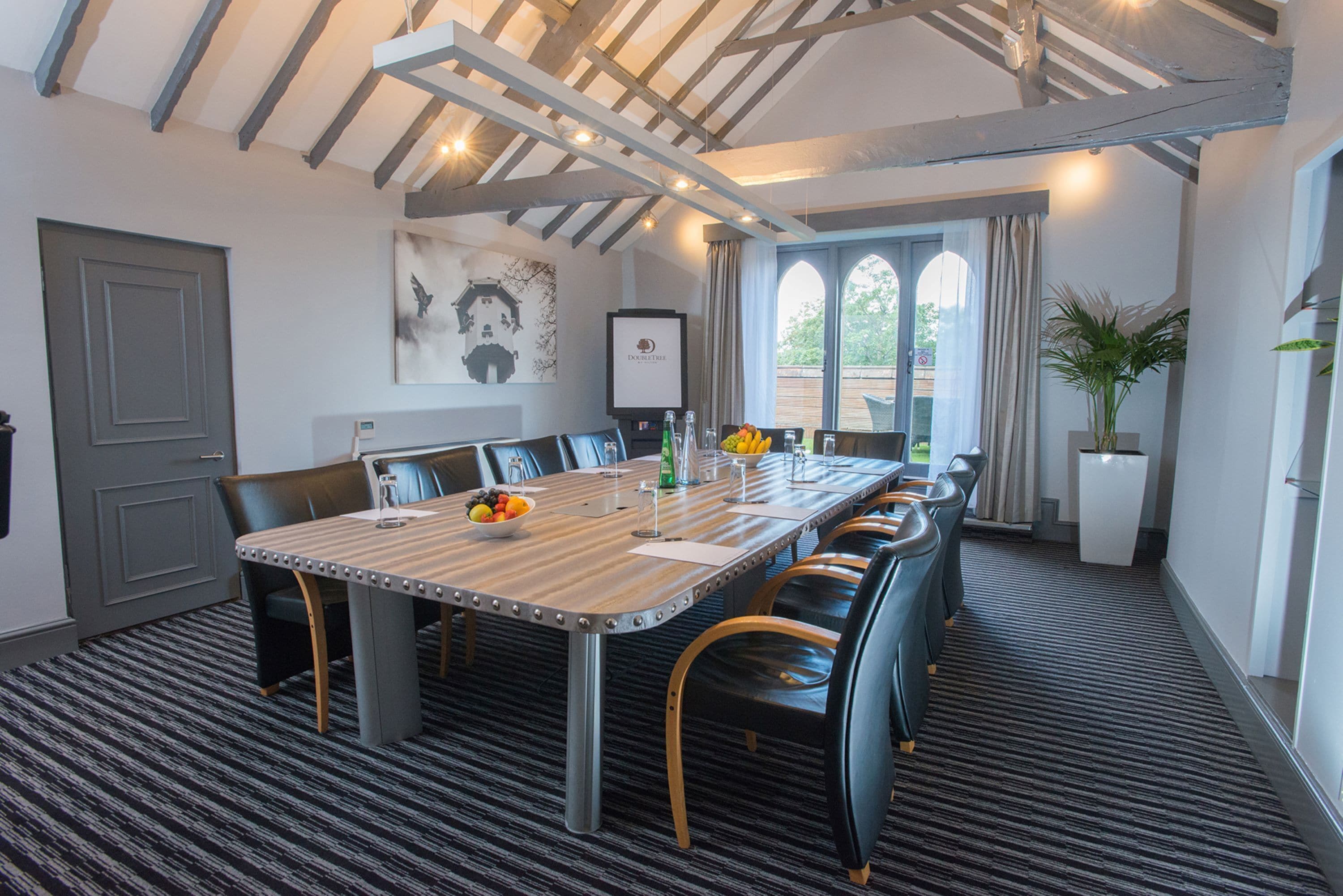 A conference room with a long table, chairs, and a potted plant.